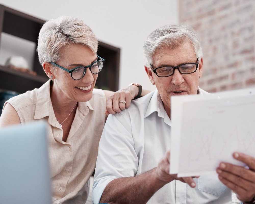 Älteres Ehepaar, Laptop und Dokument für Finanzplanung, Ersparnisse und Steuern im Haus. Ruhestand, Papierkram und glücklicher Mann und Frau mit Rechnung, Rente oder Versicherung, Finanz- und Vermögensverwaltung.